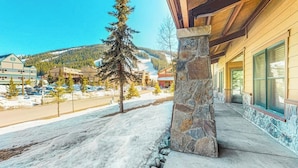 Ein Gebäude mit einer Steinsäule, einer Veranda und Blick auf eine verschneite Landschaft mit Bäumen und Gebäuden im Hintergrund.