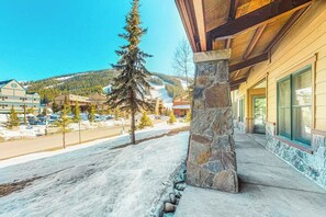 Ein Gebäude mit einer Steinsäule, einer Veranda und Blick auf eine verschneite Landschaft mit Bäumen und Gebäuden im Hintergrund.
