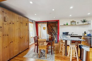 A kitchen with wooden cabinets, a dining table with chairs, a bar area, and a stainless steel sink. - Ground-Floor Condo with WiFi, Laundry & Prime Location - Walk Everywhere (Frisco)