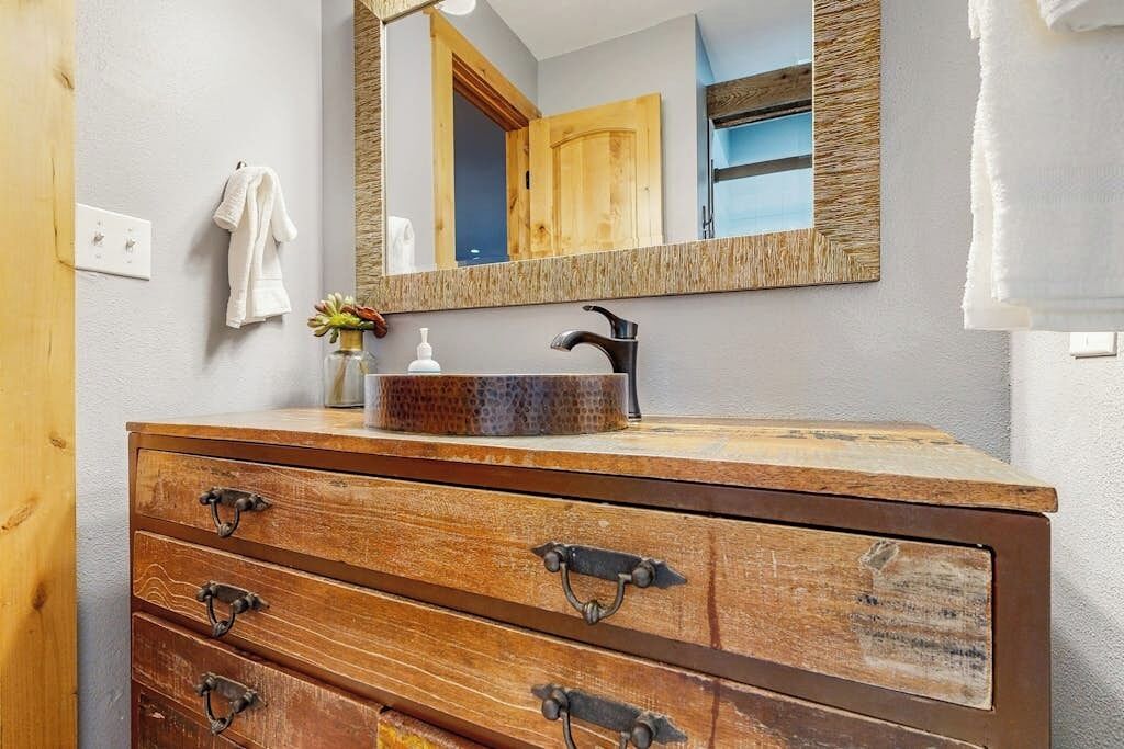 A bathroom with a wooden vanity, a mirror, a sink, and a towel rack.