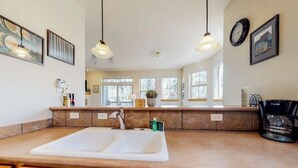 A kitchen with a large island, pendant lights, and a view of the outside.