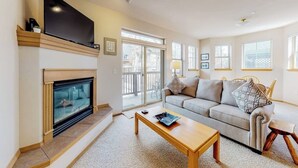 A living room with a fireplace, a sofa, a coffee table, and a TV mounted on the wall.