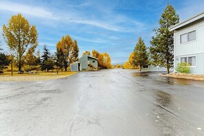 A paved driveway leading to a building with a small shed in the center. - Ground-Floor, All-Seasons Condo with Shaded Deck and Gas Fireplace (Fraser)
