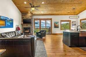A spacious living area with a fireplace, a sofa, a dining area, and a kitchen. - Large mountain home with epic views, hot tub, & gas fireplace (Grand Lake)
