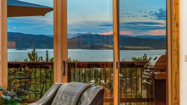 A room with a view of a lake and mountains, a grill, and a chair. - Large mountain home with epic views, hot tub, &  gas fireplace (Grand Lake)