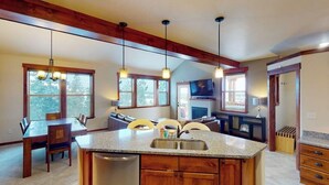 A kitchen with a central island, wooden cabinets, a dishwasher, and pendant lighting. - Top-floor condo with private hot tub, amazing mountain view & gas fireplace (Fraser)