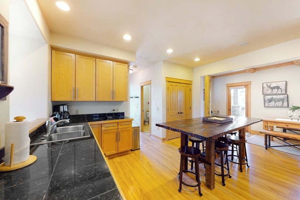A kitchen with wooden cabinets, a marble countertop, and a central island with stools.