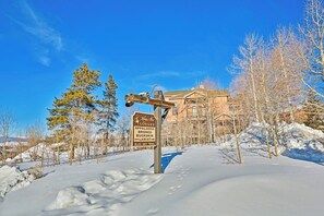 Ein verschneiter Weg mit einem Wegweiser, der die Richtung zu Lodges und Wanderwegen zeigt.
