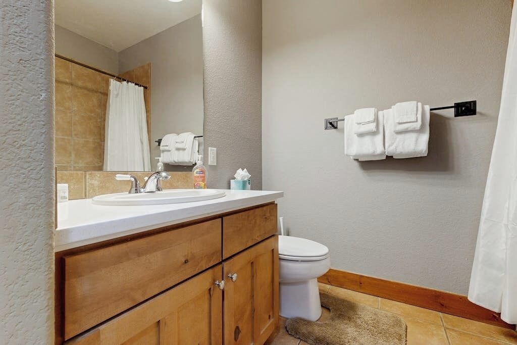 A bathroom with a wooden vanity, a sink, a toilet, and a towel rack.