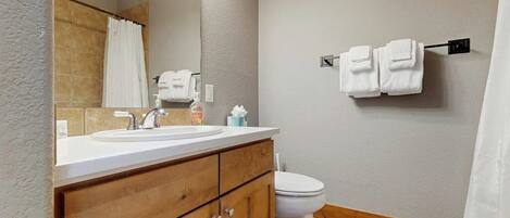 A bathroom with a wooden vanity, a sink, a toilet, and a towel rack.