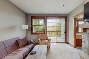 A living room with a sofa, armchair, coffee table, and a fireplace. - Family home w/private washer/dryer, free WiFi, shared hot tub, & gas fireplace (Granby)