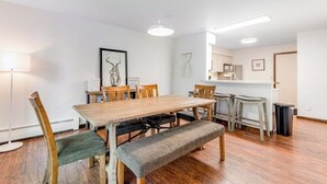 Un comedor con una mesa y sillas de madera, un banco y una cocina al fondo.