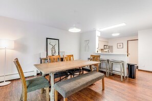 A dining area with a wooden table and chairs, a bench, and a kitchen in the background. - Dog & Family-Friendly Home with Firepit, Deck, Fireplace, W/D, & Free WiFi (Frisco)