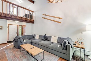 A modern living room with a sectional sofa, a wooden coffee table, and a staircase leading to an upper level. - Dog & Family-Friendly Home with Firepit, Deck, Fireplace, W/D, & Free WiFi (Frisco)