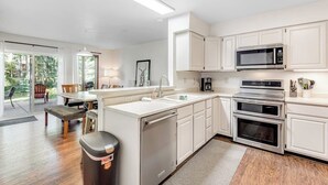 Una cocina moderna con gabinetes blancos, microondas integrado y un horno doble.