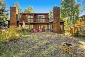 A wooden cabin with a deck, two red chairs, and a fire pit. - Dog & Family-Friendly Home with Firepit, Deck, Fireplace, W/D, & Free WiFi (Frisco)