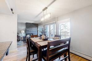 A dining area with a wooden table, chairs, and a modern chandelier. - Modern Waterfront Condo w/ Mountain View, W/D, & High Speed WiFi - Near Skiing (Frisco)