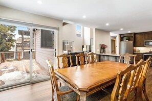 Eine moderne Küche mit Essbereich, großen Fenstern und einer Schiebeglastür zu einer Terrasse.