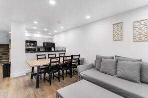 A modern kitchen with white cabinets, a dining table with chairs, and a grey sofa. - Mountain-view townhome with balcony, gas fireplace, WiFi, & W/D - great location (Frisco)