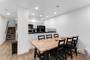A modern kitchen with white cabinets, a black refrigerator, and a wooden dining table with black chairs. - Mountain-view townhome with balcony, gas fireplace, WiFi, & W/D - great location (Frisco)