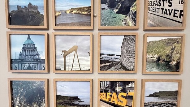 En væg med flere indrammede fotografier af forskellige landskaber og kendte steder.