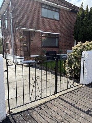 A brick house with a front door, a small porch, and a metal gate. - 3BD Cozy Family Retreat for 5 (Belfast)