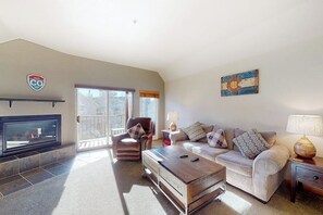 A living room with a fireplace, a sofa, a coffee table, and a TV. - Peak-view townhome with convenient central location, decks & free EV charger (Frisco)