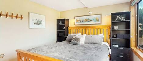 A bedroom with a bed, wooden headboard, bedside tables, a wardrobe, and a window.