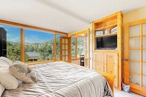 Ein Schlafzimmer mit einem großen Bett, einem Fernseher und einem Holzkabinett mit Glastüren.