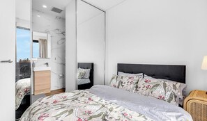 A modern bedroom with a large bed, a nightstand, a mirror, and a bathroom with a marble wall.
