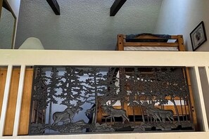 Ein Zimmer mit einem Etagenbett, einer dekorativen Metallwand mit Tierdarstellungen und einem gerahmten Bild an der Wand.