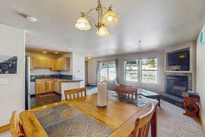 A spacious living area with a dining table, a fireplace, and a kitchen in the background. - Convenient Mountain Condo w/Free WiFi, Mtn Views, Private Washer/Dryer, & Cable (Fraser)
