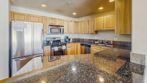 A kitchen with wooden cabinets, stainless steel appliances, granite countertops, and a microwave. - Convenient Mountain Condo w/Free WiFi, Mtn Views, Private Washer/Dryer, & Cable (Fraser)