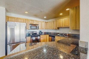 A kitchen with wooden cabinets, stainless steel appliances, granite countertops, and a microwave. - Convenient Mountain Condo w/Free WiFi, Mtn Views, Private Washer/Dryer, & Cable (Fraser)