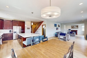 A spacious kitchen with a central island, wooden dining table, and modern pendant lighting. - Gorgeous mountain home with deck, pool table, fast WiFi & fireplace - near town (Tabernash)