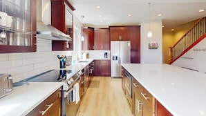 Una cocina moderna con armarios de madera, electrodomésticos de acero inoxidable y encimera blanca.