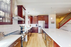 A modern kitchen with wooden cabinets, stainless steel appliances, and a white countertop. - Gorgeous mountain home with deck, pool table, fast WiFi & fireplace - near town (Tabernash)