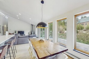 Eine moderne Küche mit einem Holztisch, Barhocker und einem großen Fenster.