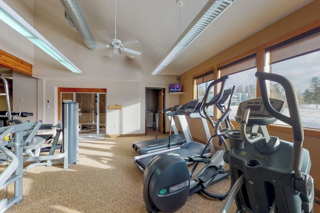 Ein Fitnessraum mit Laufbändern, Crosstrainern und Gewichtsmaschinen.