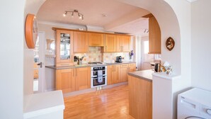 Una cocina con armarios de madera, una estufa a gas y una lavadora.