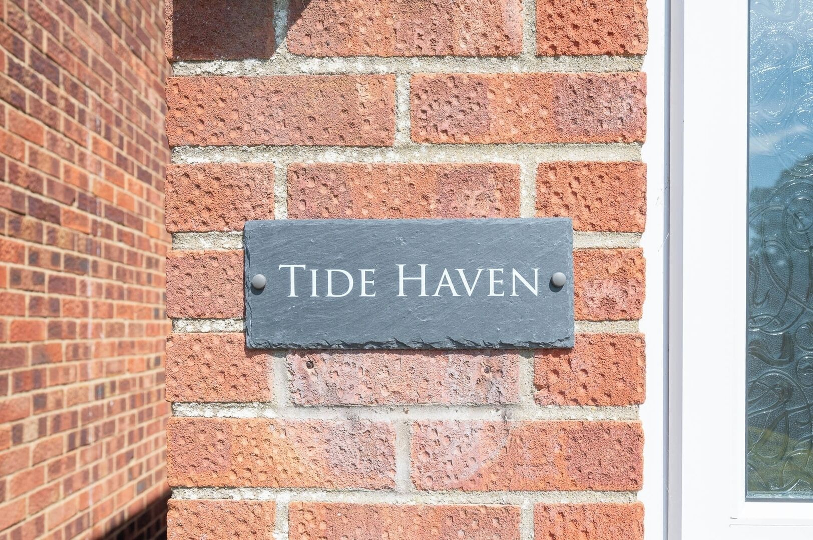 A slate sign with 'Tide Haven' on a brick wall.