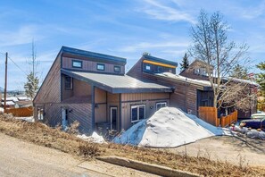 Ein modernes, zweistöckiges Gebäude mit Satteldach, sichtbarer Garage und einer großen Menge Baumaterialien.