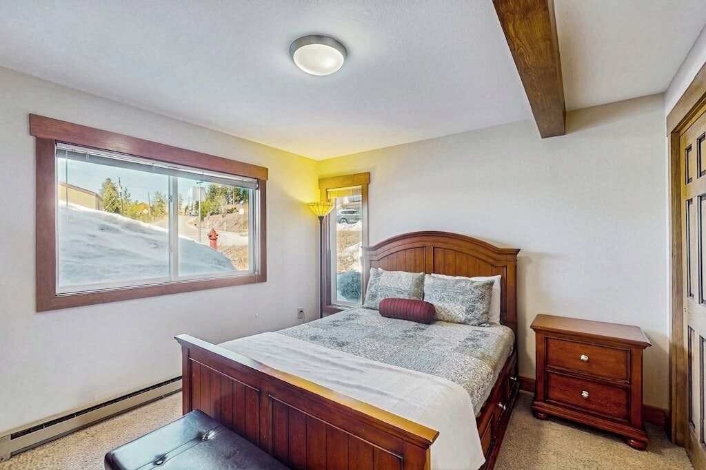 A bedroom with a bed, a window, a bedside table, and a ceiling light.