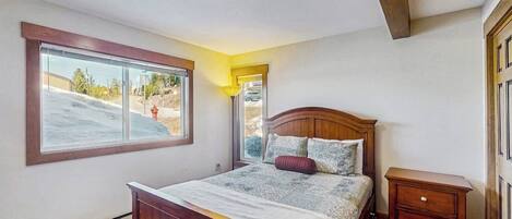 A bedroom with a bed, a window, a bedside table, and a ceiling light.