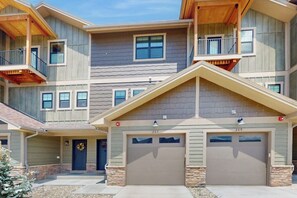 A multi-story residential building with a garage, a balcony, and a door with a wreath. - Charming townhome in central locale with fireplace & balcony - dog-friendly (Granby)