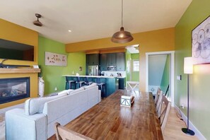A modern kitchen with a dining area, a sofa, and a fireplace. - Charming townhome in central locale with fireplace & balcony - dog-friendly (Granby)