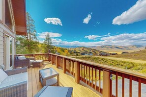 Eine Terrasse mit Gartenmöbeln, Blick auf ein Tal und ein klarer Himmel.