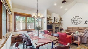 Uma sala de jantar com uma mesa de madeira, cadeiras vermelhas e um candelabro.