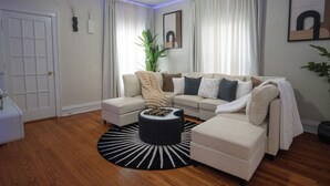 A living room with a sectional sofa, a round coffee table, and a potted plant. - 6BR Apt • Workspace • Near Lakefront + Red Line (Chicago)