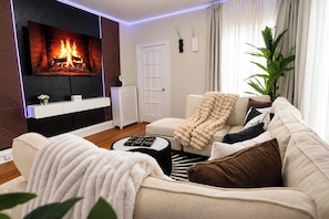 A modern living room with a fireplace, a sofa, a coffee table, and a plant.